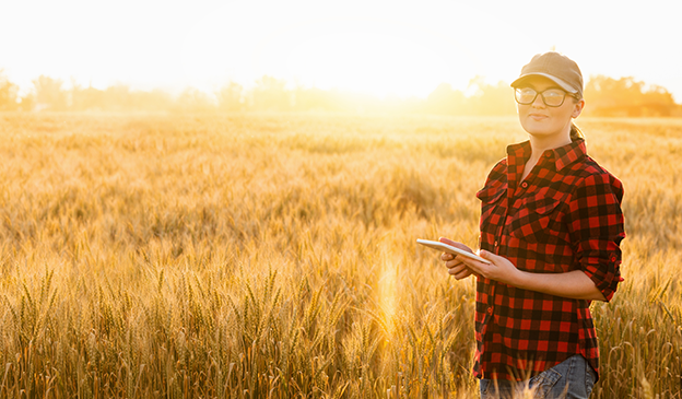 Woman standing in farm field holding tablet